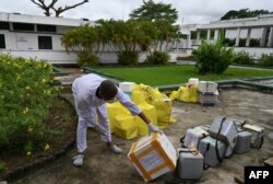 FILE - A lab technician at the Pasteur Institute of Ivory Coast looks at collected samples to be tested for the coronavirus and other samples for analysis, near Abidjan, May 11, 2020.