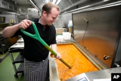 A volunteer chef from the charity 'The Felix Project' stirs a curry at their storage hub in London, Wednesday, May 4, 2022. (AP Photo/Frank Augstein)