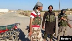 Islamic State fighters stand along a street in the countryside of the Syrian Kurdish town of Kobani, after taking control of the area, Oct. 7, 2014.