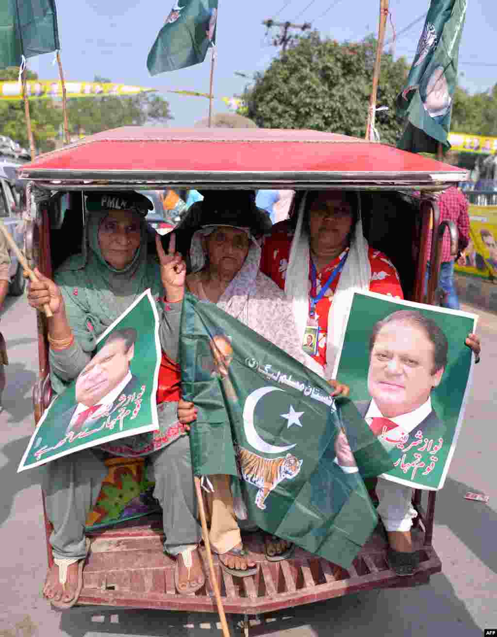 پاکستان مسلم لیگ (ن) کی خواتین کارکنان ایک چنگچی میں سوار ہوائی اڈے جانے والے مرکزی جلوس میں شرکت کے لیے جا رہی ہیں۔