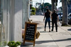 Un letrero anuncia límites a la cantidad de clientes afuera de una tienda, el miércoles 18 de noviembre de 2020, en el área de West Hollywood, en Los Ángeles. El condado de Los Ángeles impuso nuevas restricciones a las empresas el martes.