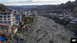 Trabajadores municipales utilizan maquinaria pesada para retirar fango del lecho del río Irpavi, donde lluvias persistentes dañaron varias viviendas en las márgenes, el jueves 22 de febrero de 2024, en La Paz, Bolivia.