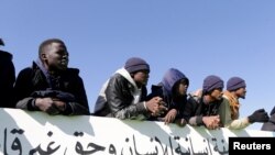 FILE—Migrants watch a football match inside the headquarters of immigration in Benghazi, Libya December 5, 2020. 