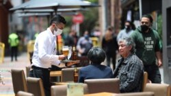 A waiter wearing a mask to curb the spread of the new coronavirus tends to a couple of customers outside a restaurant in the Usaquen neighborhood of Bogota, Colombia, Thursday, Sept. 3, 2020. Restaurants are reopening in most of Colombia as the…