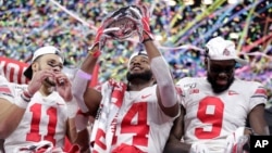 FILE - Ohio State wide receiver K.J. Hill (14) holds the trophy following the team's 34-21 win over Wisconsin in the Big Ten championship NCAA college football game, Dec. 8, 2019, in Indianapolis. The Big Ten has announced they would not have a fall football season.
