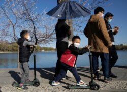 Visitors wear masks at a park during a sunny day in Beijing, March 19, 2020. China has only just begun loosening draconian travel restrictions within the country amid the coronavirus outbreak.