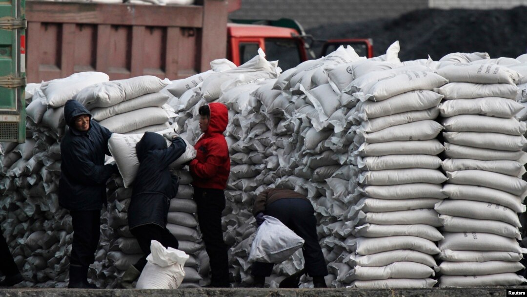 Warga Korea Utara mendistribusikan berkarung-karung terigu impor di bantaran sungai Yalu, dekat kota Sinuiju, Korea Utara. (Reuters/Jacky Chen) 
