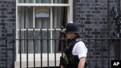 A police officer walks past a drawing of a rainbow with the words "we are in this together" displayed in one of the windows of 10 Downing Street in London, April 9, 2020. 