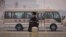 FILE - A vehicle carries the delegates passing by Tiananmen Square as a police officer stands guard next to main road.
