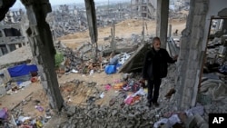 FILE - A man stands in rubble of his house, destroyed in this year's Israel-Hamas conflict, in the Shijaiyah neighborhood of Gaza City, Nov. 24, 2014.