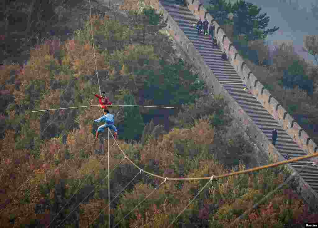 Adili Wuxor (back, in red), who is known as "Prince of the Tightrope", and his apprentice balance on a tightrope above the Great Wall in Tianjin, China.