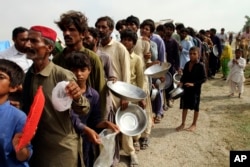 FILE - Flood affected people stand in a long line with utensils to get food distributed by Pakistani Army troops in a flood-hit area in Rajanpur, district of Punjab, Pakistan on August 27, 2022. (AP Photo/Asim Tanveer, File)