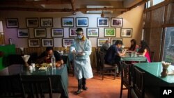 A waiter wearing personnel protection kit serves food in a restaurant in Gauhati, India, June 10, 2020.