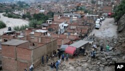 Photo provided by government's Andina news agency shows people standing next to several trucks partially covered by a mudslide caused by heavy rains in Chosica, March 24, 2015.