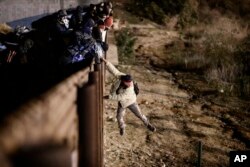A migrant jumps the border fence to get into the U.S. side to San Diego, Calif., from Tijuana, Mexico, Jan. 1, 2019.