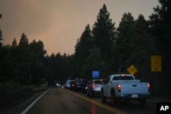 Motorists line up in the outskirts of town as smoke from the Line Fire fills the air Sept. 7, 2024, in Running Springs, California.