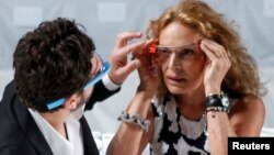 FILE - Google founder Sergey Brin (L) adjusts a pair of Project Glass glasses on designer Diane von Furstenberg before the rehearsal for von Furstenberg's Spring/Summer 2013 collection show during New York Fashion Week.