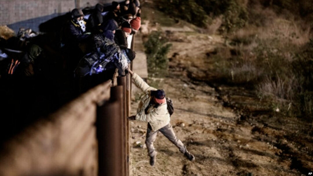 Seorang migran melompat dari pagar perbatasan AS-Meksiko untuk masuk ke wilayah AS di dekat Tijuana, Meksiko, 1 Januari 2019 lalu. 