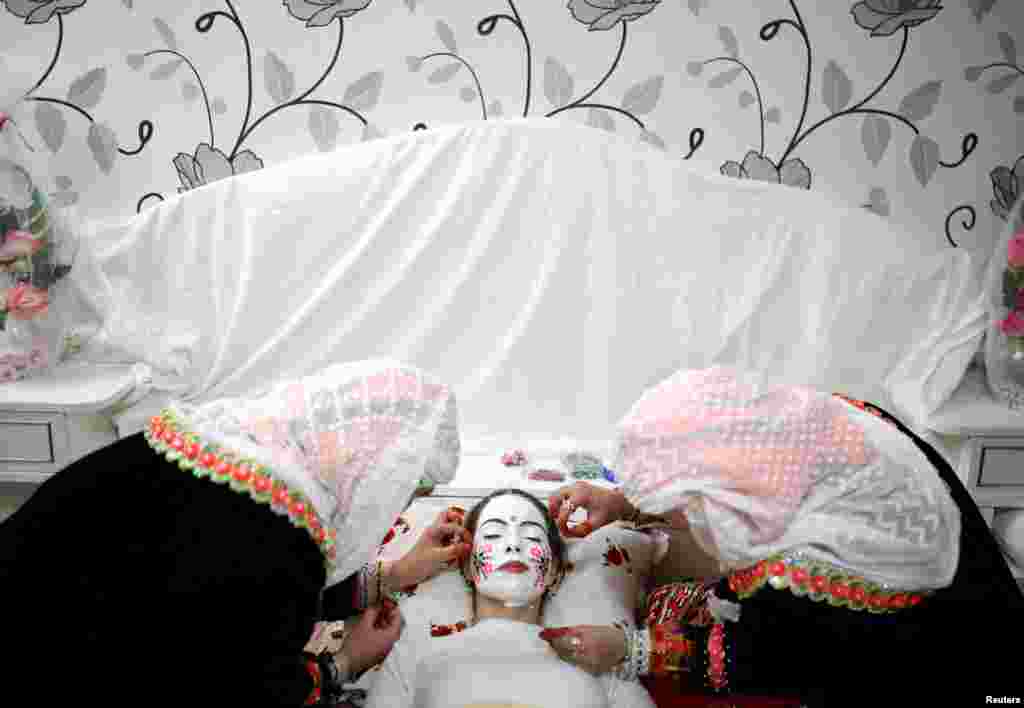 Bulgarian Muslim bride Kimile Avdinova has makeup applied to her face during her wedding ceremony in the village of Ribnovo, in the Rhodope Mountains, Jan. 2, 2022.