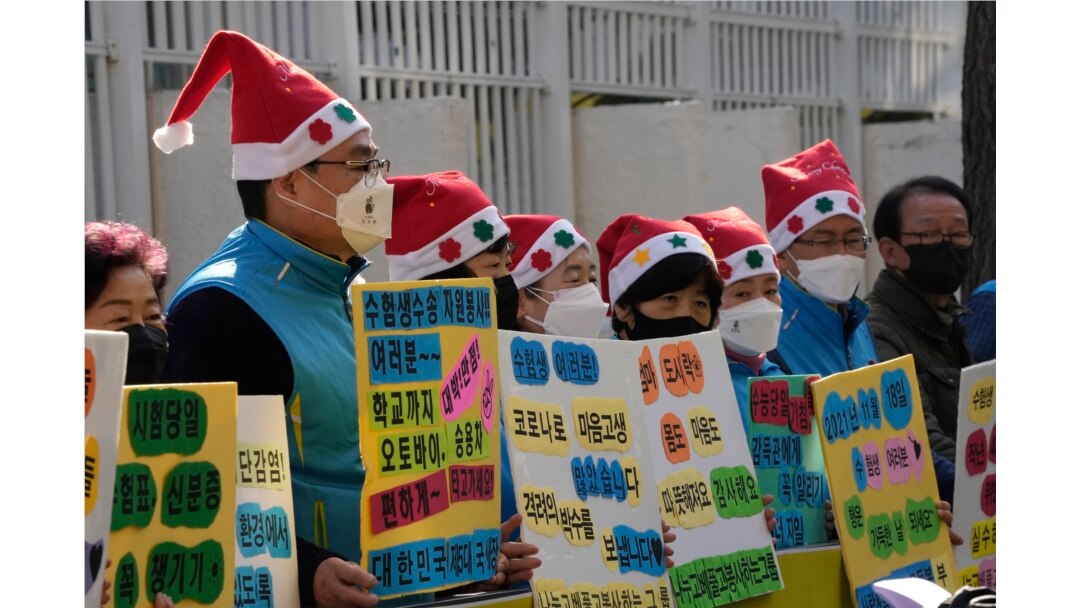 Para orang tua murid mengenakan masker, berdiri untuk mendoakan keselamatan dan kesuksesan anak-anak mereka pada malam ujian masuk perguruan tinggi di depan kompleks pemerintah di Seoul, Korea Selatan, Rabu, 17 November 2021.
