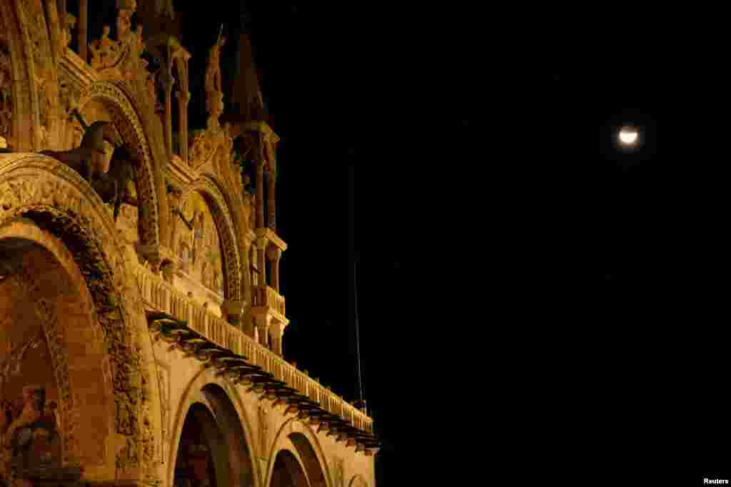 اٹلی کے شہر وینس میں&nbsp;سینٹ مارک اسکوائر کے ایک تاریخی گرجا گھر کی عمارت کے قریب سے گرہن لگے چاند کی لی گئی تصویر کا ایک منظر &nbsp;
