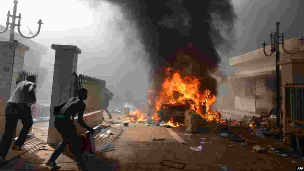 Des manifestants mettent le feu au Parlement à Ouagadougou le 30 octobre 2014. Des centaines de manifestants en colère au Burkina Faso ont pris d&#39;assaut le parlement le 30 octobre avant d&#39;y mettre le feu en protestation contre l&#39;intention de modifier la Constitution pour permettre au Président Blaise Compaoré pour étendre son règne de 27 ans. La police a tiré des gaz. AFP PHOTO / ISSOUF SANOGO 