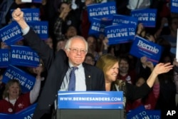 Democratic presidential candidate Senator Bernie Sanders of Vermont and his wave, Jane, acknowledge the crowd as he arrives for his caucus night rally in Des Moines, Iowa, Feb. 1, 2016.