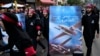 FILE - Lebanese members of Hezbollah walk barefoot as they carry a poster showing Hezbollah drones with Arabic words that reads: "We are coming," in the southern suburb of Beirut, Lebanon, Aug. 9, 2022. 