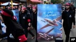 FILE - Lebanese members of Hezbollah walk barefoot as they carry a poster showing Hezbollah drones with Arabic words that reads: "We are coming," in the southern suburb of Beirut, Lebanon, Aug. 9, 2022. 