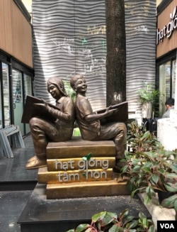 Mấy tụ điểm để du khách chụp hình; trái, bức tượng đồng "hai bé ngồi chống lưng đọc sách", phải, cô gái ngồi đàn guitare live trong một khu đọc sách ngoài trời. [photo by Ngô Thế Vinh]
