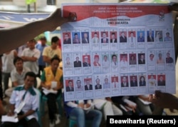 Warga menyaksikan petugas penyelenggara pemilu menunjukkan surat suara saat penghitungan suara di TPS di Jakarta, 9 April 2014. (Foto: REUTERS/Beawiharta)