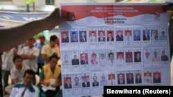 Warga menyaksikan petugas penyelenggara pemilu menunjukkan surat suara saat penghitungan suara di TPS di Jakarta, pada 9 April 2014. (Foto: Reuters/Beawiharta)