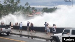 Incoming waves tower over bystanders in Kona, Hawaii, U.S., Aug. 23, 2018 in this still image from video obtained from social media. (Ryan Leinback)