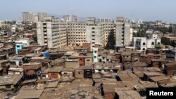 FILE - High-rise residential buildings are seen behind a cluster of houses at a slum in Mumbai, May 6, 2014.