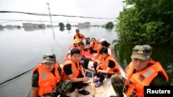 Petugas polisi paramiliter mengevakuasi penduduk desa yang dilanda banjir dengan perahu di daerah Yongxiu di Jiujiang, Provinsi Jiangxi, China 14 Juli 2020. (Foto: China Daily via REUTERS)