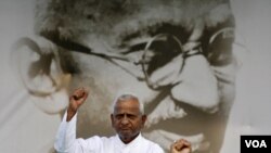 Anna Hazare mengacungkan kepalan tangan kepada para pendukungnya dengan latar belakangan gambar Mahatma Gandhi di New Delhi (19/8). Hazare memulai mogok makan 15 hari untuk mendesak penerapan UU anti-korupsi yang lebih tegas.