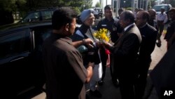 India's Prime Minister Manmohan Singh, center, is greeted by Chief Postmaster General John Samuel, right presenting a bouquet, in Srinagar, June 25, 2013. 