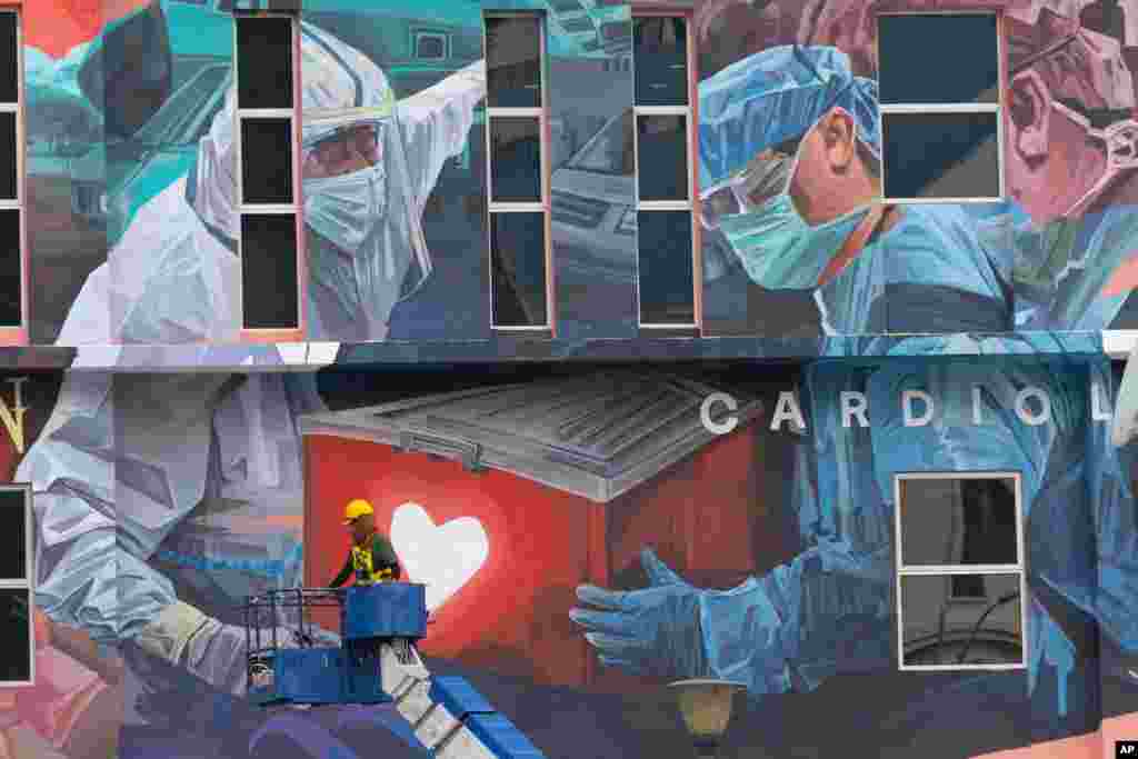 A worker adds finishing touches to a giant mural tribute to frontline workers in the COVID-19 pandemic, outside a hospital in Kuala Lumpur, Malaysia.