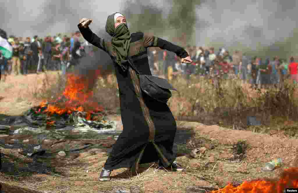 A girl hurls stones during clashes with Israeli troops at a protest where Palestinians demand the right to return to their homeland at the Israel-Gaza border, east of Gaza City.