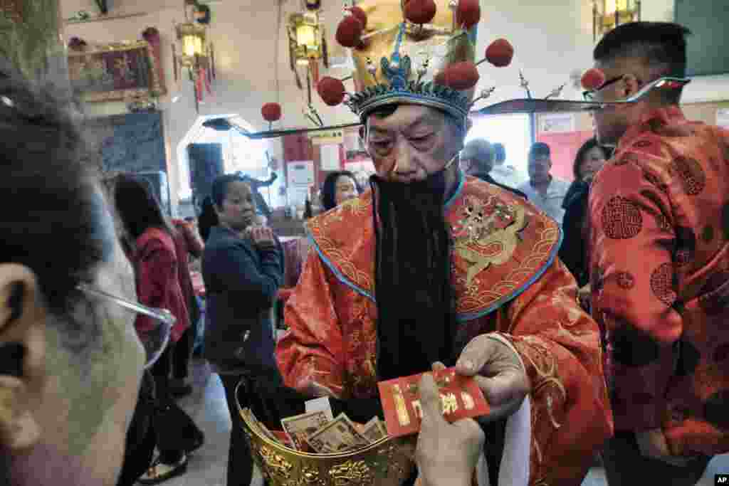 2018年2月16日，一位打扮成财神的男子在洛杉矶唐人街的天后庙向访客发红包。