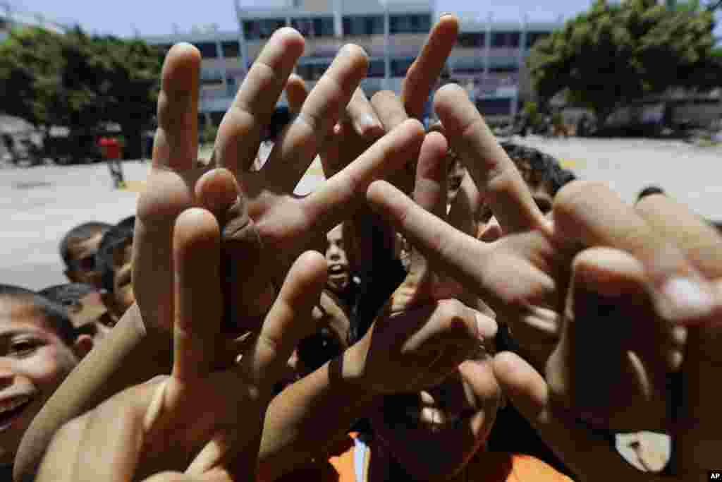 Anak-anak Palestina, mengacungkan jari-jari mereka membuat tanda V, bermain dengan fotografer di sebuah sekolah Perserikatan Bangsa - Bangsa yang merupakan tempat ratusan keluarga mencari perlindungan setelah melarikan diri dari tempat tinggal mereka akibat adanya serangan berat dari pasukan Israel, di&nbsp; kamp pengungsi Jebaliya, jalur Gaza. &nbsp;