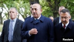 FILE - Turkey's Foreign Minister Mevlut Cavusoglu, center, walks to pay respects to the victims of the mosque shooting, in Christchurch, New Zealand, March 18, 2019.