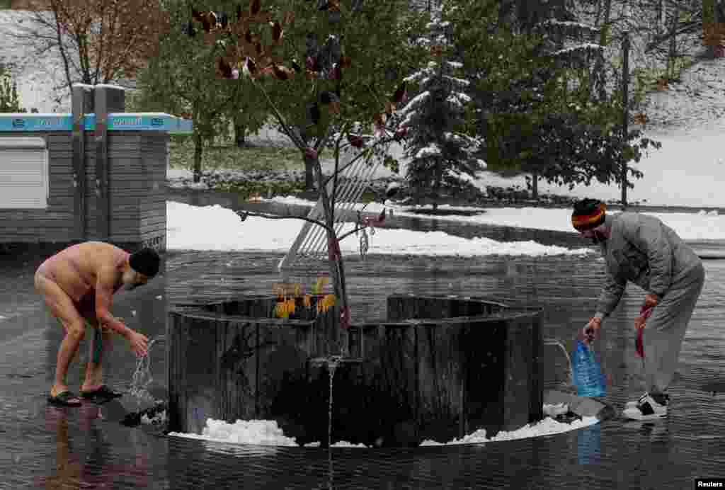 Residents are seen near a city well during the first snowfall, amid Russia&#39;s attack on Ukraine, in Kharkiv, Ukraine.