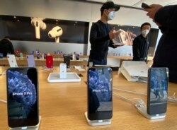 FILE - Staff chats with customers at an apple store in Beijing, Feb. 19. Factories that make the world's smartphones, toys and other goods are struggling to reopen after a virus outbreak idled China's economy.