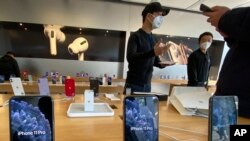 FILE - Staff members chat with customers at an Apple store in Beijing, Feb. 19, 2020. 