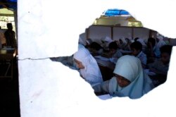 Siswa SMP terlihat melalui lubang di dinding saat mengikuti pembelajaran di gedung sekolah sementara di Bantul, Yogyakarta, 25 Mei 2007. (Foto: REUTERS/Dwi Oblo)