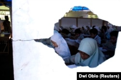 Siswa SMP terlihat melalui lubang di dinding saat mengikuti pembelajaran di gedung sekolah sementara di Bantul, Yogyakarta, 25 Mei 2007. (Foto: Ilustrasi/REUTERS/Dwi Oblo)