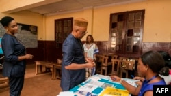 The Governor of the Central Region of Cameroon, Paul Naseri Bea's identity document is checked by electoral staff before proceeding to cast his vote in the general and municipal elections in Yaounde on Feb. 9, 2020. 