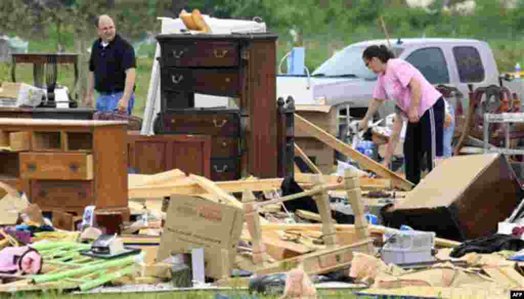 Carla Arendal, right, looks for items to save on Tuesday, April 26, 2011, after her home was destroyed by a tornado in Vilonia, Ark. Arendal and her husband were in the home during the storm but were uninjured. Helping to recover items is Arendal's minist