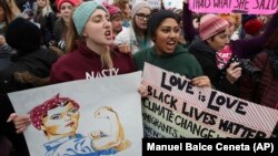 Kaelyn Warne, left, and Marvi Ali both former students of College of William & Mary in Williamsburg, Va., join protest with other women against President Donald Trump.